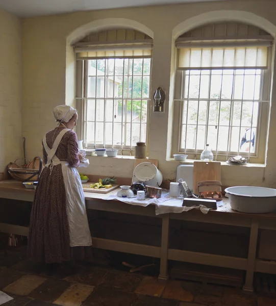 Victorian Kitchen maid preparing food by window. — Stock Photo, Image