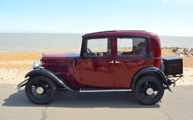 : Vintage koyu kırmızı Austin Motor araba sahil şeridi üzerinde park.