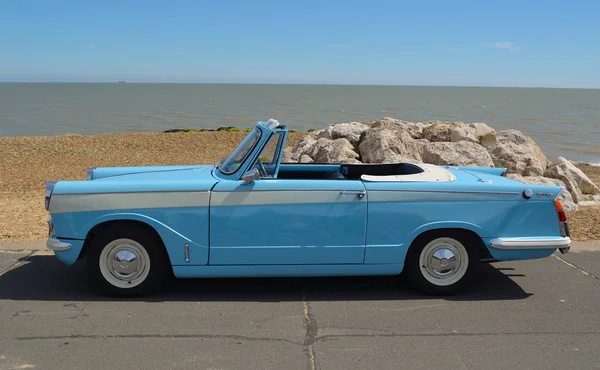 Klasické světle modré Triumph Herald otevřít horní motorické auto zaparkované na nábřežní promenádě. — Stock fotografie