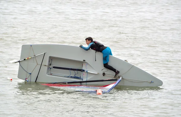 Vela volcada bote con el joven tratar de corregirlo, en el mar en Felixstowe Suffolk Inglaterra . — Foto de Stock