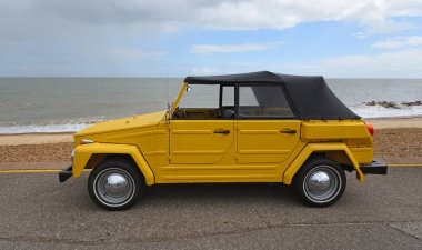Felixstowe, Suffolk, İngiltere - Mayıs 04, 2025: Klasik VW Volkswagen Tipi 181 Safari, Thing veya Trekker arka planda deniz kenarına park edilmiş.