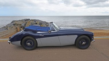 Felixstowe, Suffolk, İngiltere - 05 Mayıs 2024: Klasik Austin-Healey 3000 MkIII deniz kenarında arka planda park halindedir..