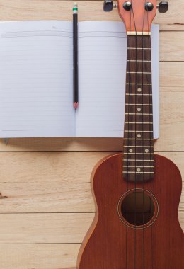 boş defter ile kalem ve ukulele üzerine ahşap masa