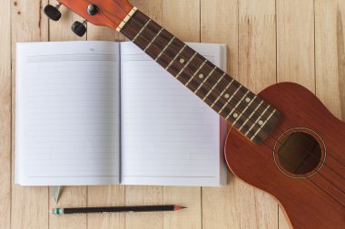 boş defter ile kalem ve ukulele üzerine ahşap masa