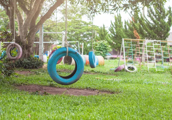 Balanço de pneu pendurado em uma árvore no parque infantil — Fotografia de Stock