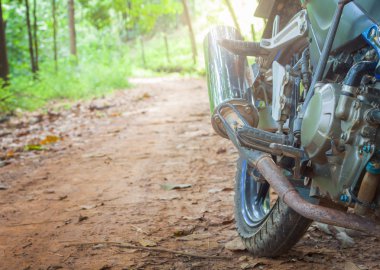 güneş ışığı ile toprak yola Park motosiklet.