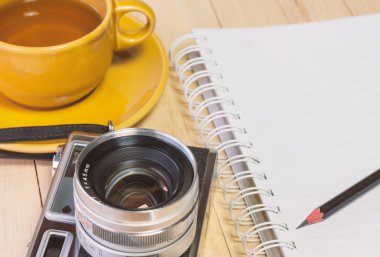 Retro film kameraları ve ahşap arka plan üstünde defter.