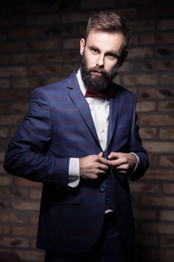 sakallı ve tuğla duvar tarafından kalmak ve kadar düğmelerini takım elbiseli adam