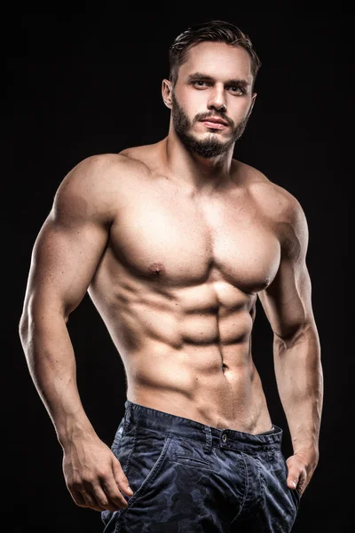 Attraktiv bodybuilder Sportsman visar perfekt kropps muskler på svart bakgrund; — Stockfoto