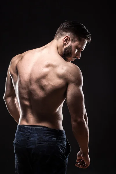 Aantrekkelijke bodybuilder sportman toont perfecte lichaamsspieren op zwarte achtergrond; — Stockfoto