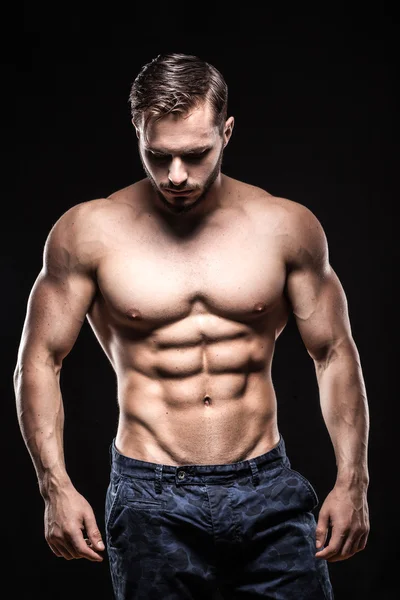 Aantrekkelijke bodybuilder sportman toont perfecte lichaamsspieren op zwarte achtergrond; — Stockfoto