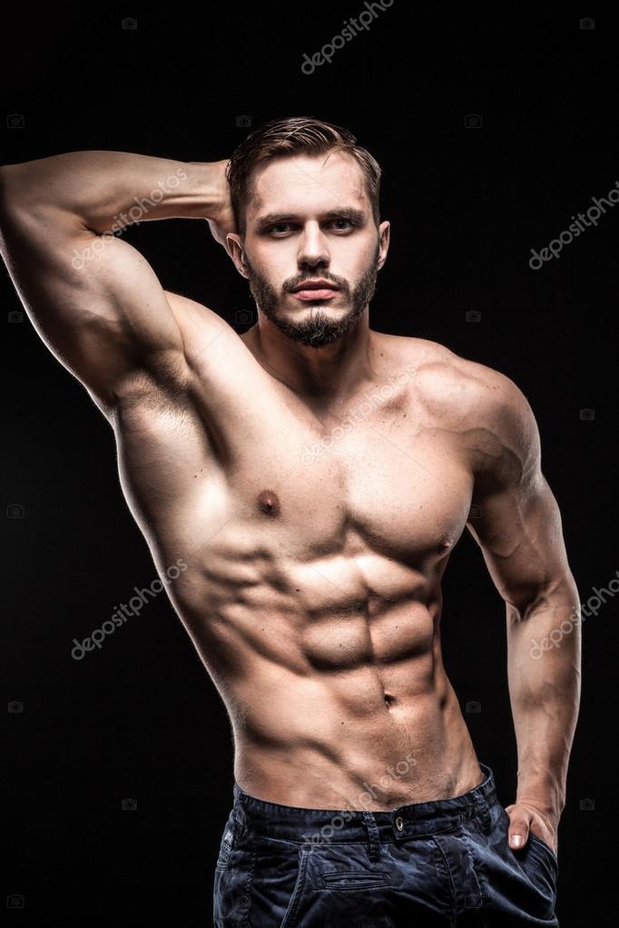 Attractive bodybuilder sportsman shows perfect body muscles on black