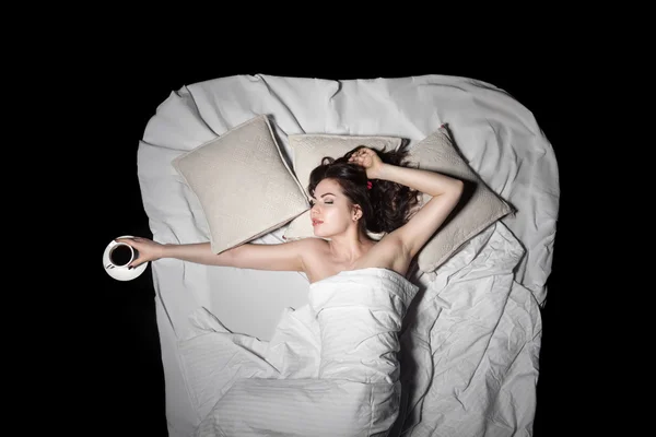 年轻女性躺在床上保持咖啡，从上面查看; — 图库照片