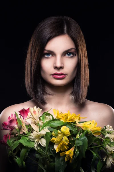 Ung brunett flicka håller blommor på svart bakgrund — Stockfoto