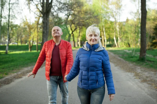 Feliz pareja de ancianos tomados de la mano y caminar ; — Foto de Stock