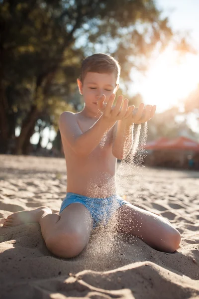 Счастливый ребенок играет с песком на пляже ; — стоковое фото