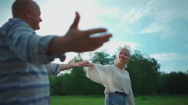 Parkta buluşan mutlu çift gülümseyip el ele tutuşuyorlar.