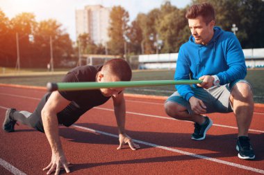 Spor adamı spor yapıyor ya da kişisel fitness eğitmeniyle dışarıda egzersiz yapıyor.