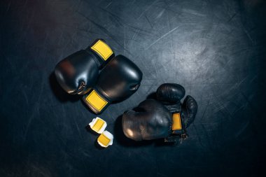 Siyah arka planda boks eldivenleri, kask ve bandaj bandı üst görünümü