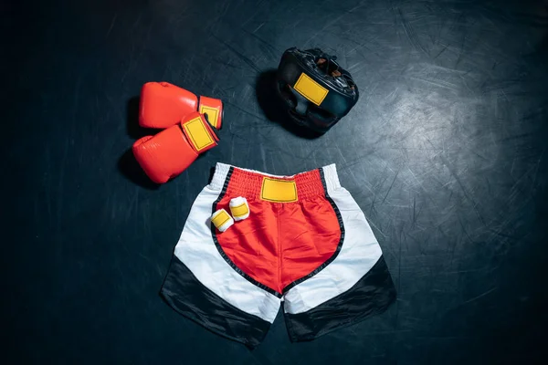 Vista superior de guantes de boxeo, pantalones cortos, casco y cinta adhesiva sobre fondo negro —  Fotos de Stock