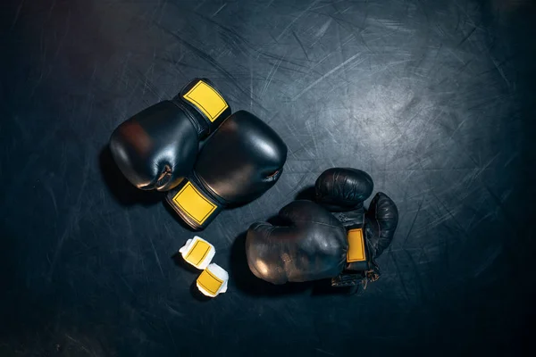 Vista superior de guantes de boxeo, casco y cinta adhesiva sobre fondo negro — Foto de Stock