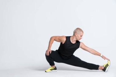 Sportif adam esneme egzersizi yapıyor ve beyaz arka planda yoga minderi üzerinde egzersiz yapıyor.