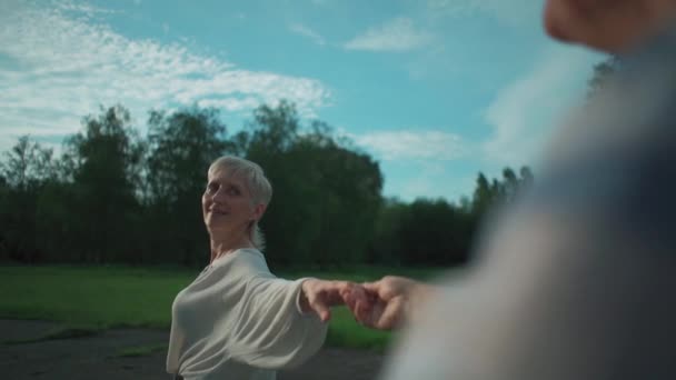 Šťastný starší pár na rande v parku úsměv, chůze a držení se za ruce — Stock video
