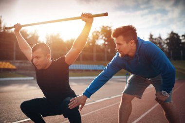 Spor adamı spor yapıyor ya da kişisel fitness eğitmeniyle dışarıda egzersiz yapıyor.