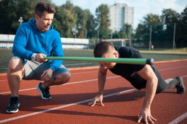 Spor adamı spor yapıyor ya da kişisel fitness eğitmeniyle dışarıda egzersiz yapıyor.