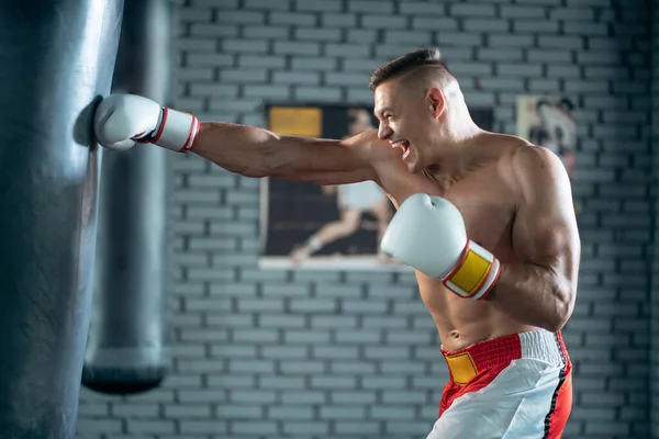 Svalnatý boxer mužský trénink s boxovací pytel v tělocvičně — Stock fotografie