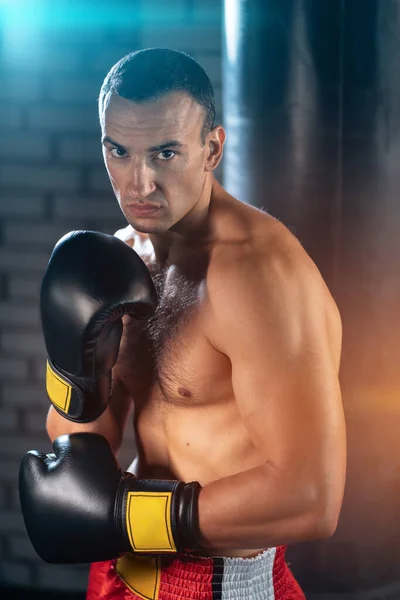 Aggressive muscular boxer sport man training in black boxing gloves in gym — Stock Photo, Image