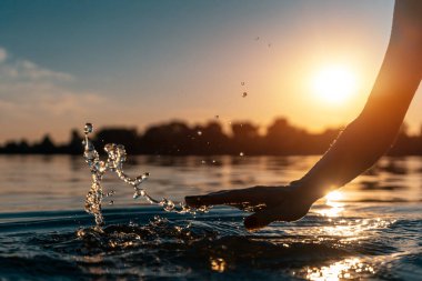 Gün batımında kız eli siluetine yakın çekim yapmak ya da gölde su sıçratmak.