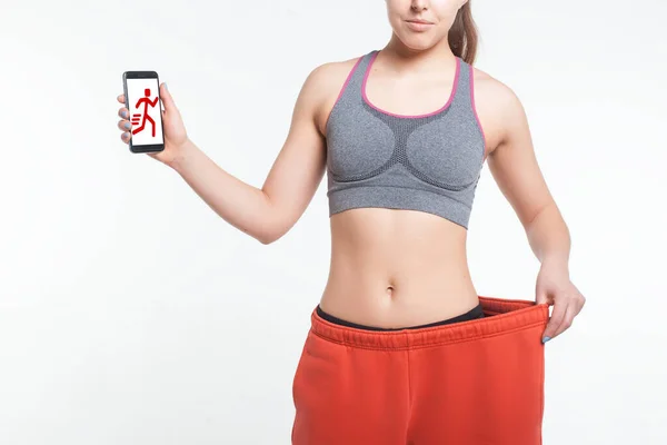 Молода жінка після онлайн-тренувань зі схудненням з смартфоном ізольовано — стокове фото