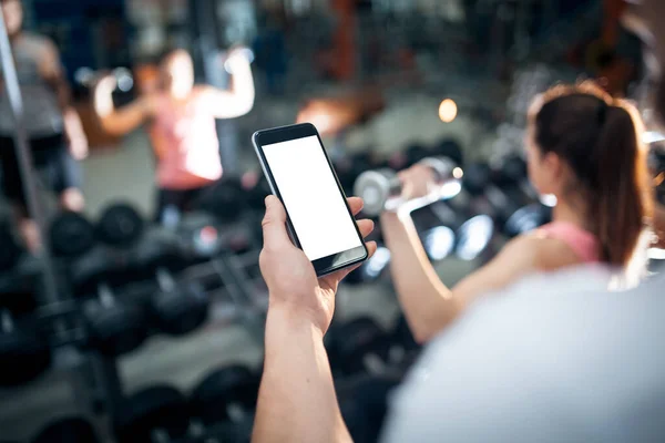 Entrenamiento en línea personal con el teléfono móvil o aplicación de teléfono inteligente en el gimnasio — Foto de Stock