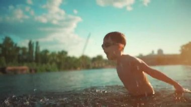 Su gözlüklü aktif bir çocuk gölde, nehirde ya da okyanusta yüzüyor ve su sıçratmaca oynuyor.