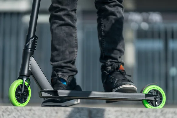 Joven adolescente en zapatilla de deporte en moderno extrema truco patada scooter en skatepark — Foto de Stock