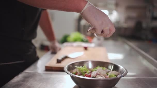 Primer plano de cocinero mano en guantes médicos poner cebolla roja en ensalada griega fresca — Vídeo de stock