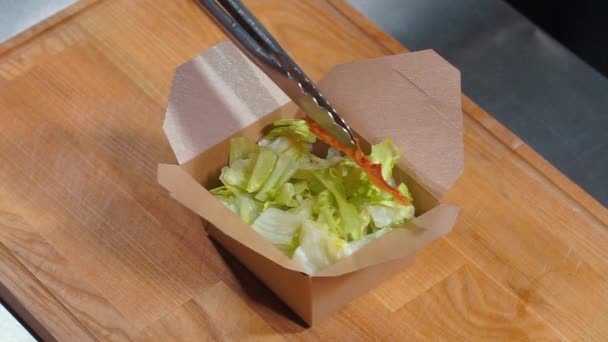 Cozinhar a mão em luvas médicas colocar salada de frango fresco césar em recipiente de comida — Vídeo de Stock