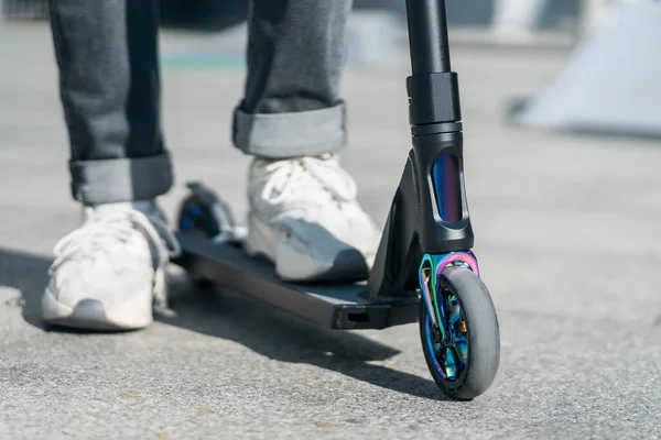 Joven adolescente en zapatilla de deporte en moderno extrema truco patada scooter en skatepark —  Fotos de Stock