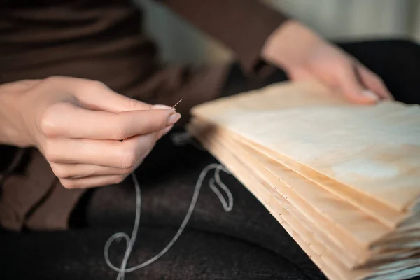 Крупним планом жіночі руки обв'язуюча книга вдома або DIY зробити книгу зі старим папером — стокове фото