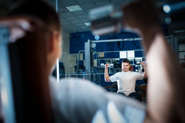 Fiatal jóképű férfi van személyes edzés vagy testmozgás súlyzókkal a tornateremben — Stock Fotó
