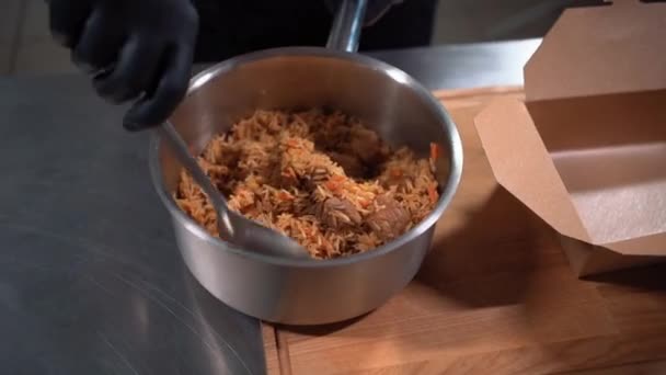 Zbliżenie kucharz gotować rękę w rękawicach medycznych umieścić pilaf lub ryż w pojemniku żywności — Wideo stockowe