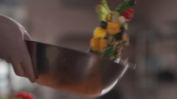 シェフは医療用手袋の混合物で手を調理するか、キッチンでボウルにギリシャサラダを投げる — ストック動画
