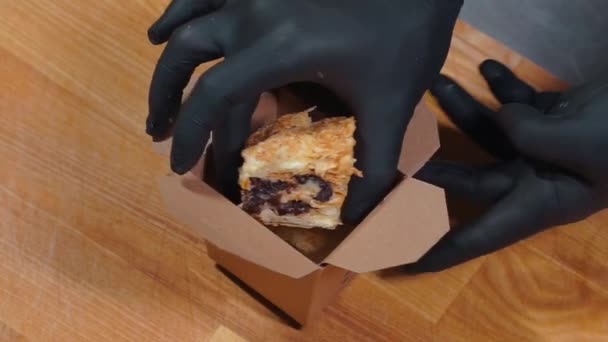Nahaufnahme von Koch Koch Hand in medizinische Handschuhe legte Kuchen Dessert in Lebensmittelbehälter — Stockvideo