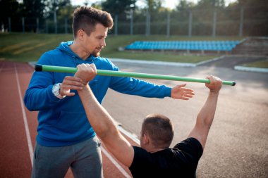 Spor adamı spor yapıyor ya da kişisel fitness eğitmeniyle dışarıda egzersiz yapıyor.