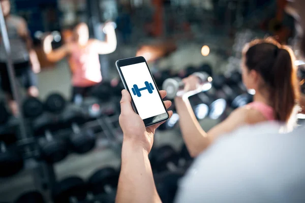 Entrenamiento en línea personal con el teléfono móvil o aplicación de teléfono inteligente en el gimnasio — Foto de Stock