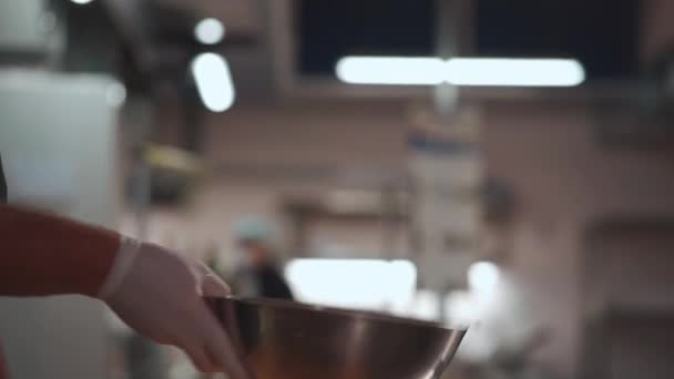 Kuchař vařit ruku v lékařské rukavici míchání nebo házet řecký salát v misce v kuchyni — Stock video