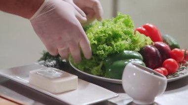 Aşçıyı kapatın. Elleri tıbbi eldivenlerle tutun. Salatayı hazırlamak için marul alın.