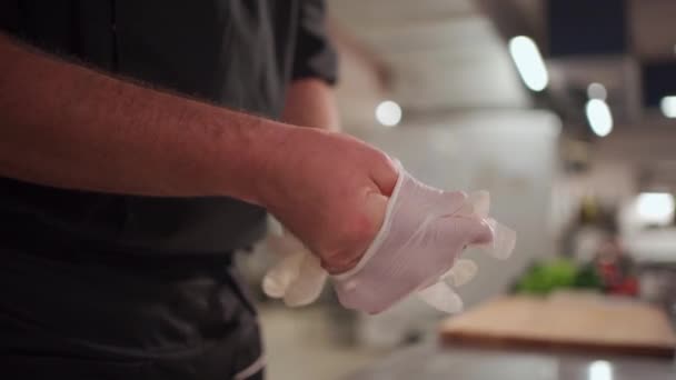 식품을 준비하기 전에 보호용 의료용 일회용 장갑을 끼고 요리하는 남성 요리사 — 비디오