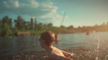 Su gözlüklü aktif bir çocuk gölde, nehirde ya da okyanusta yüzüyor ve su sıçratmaca oynuyor.